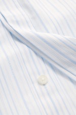 Jacquemus Casual shirt kent collar light blue/white striped close-up from above showing pure cotton fabric, soft smooth feel, fine stripe with woven logo, concealed button placket, initial patch, pin tuck, classic sport cuff, oversized fit, and rounded he