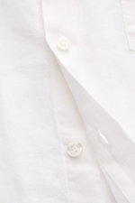 Close-up front angle of Vilebrequin Linen shirt slim collar white, showing lightweight fabric, soft feel, regular fit, narrow collar, French button placket, classic barrel cuffs, patch breast pocket, rounded hem, and tonal stitching on the hem.