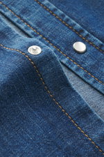 Nahaufnahme des Dondup Jeanshemds schmaler Kragen dunkelblau mit weichen Baumwollstoff, sichtbaren Druckknöpfen und dekorativer Naht aus schräger Perspektive.