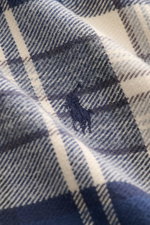 Nahaufnahme des Polo Ralph Lauren Flanellhemd Button-Down-Kragen sand/navy/grau kariert aus weichem Baumwoll-Flanell, mit klassischem Karo, tonalem Stick-Logo, fotografiert aus Detailperspektive.