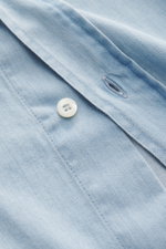 Close-up front view of Brunello Cucinelli Casual Shirt Shark Collar Light Blue showing button, pure cotton fabric with fine twill structure, soft touch, regular fit, shark collar, patched button placket, classic sport cuff, and rounded hemline.