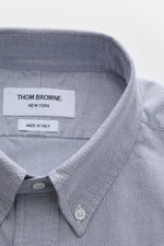 Close-up, top-down view of Thom Browne Short sleeve shirt button-down collar smoky blue, made of pure cotton Oxford fabric with a button-down collar and patch button placket. 

Description: A modern interpretation of a classic: This stylish short sleeve s