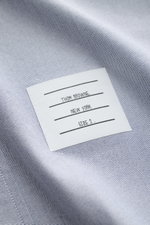 Close-up view of the Thom Browne Short sleeve shirt button-down collar smoky blue fabric and label, showcasing pure cotton Oxford texture. A modern interpretation of a classic: This stylish short sleeve shirt by THOM BROWNE is a versatile choice for sophi