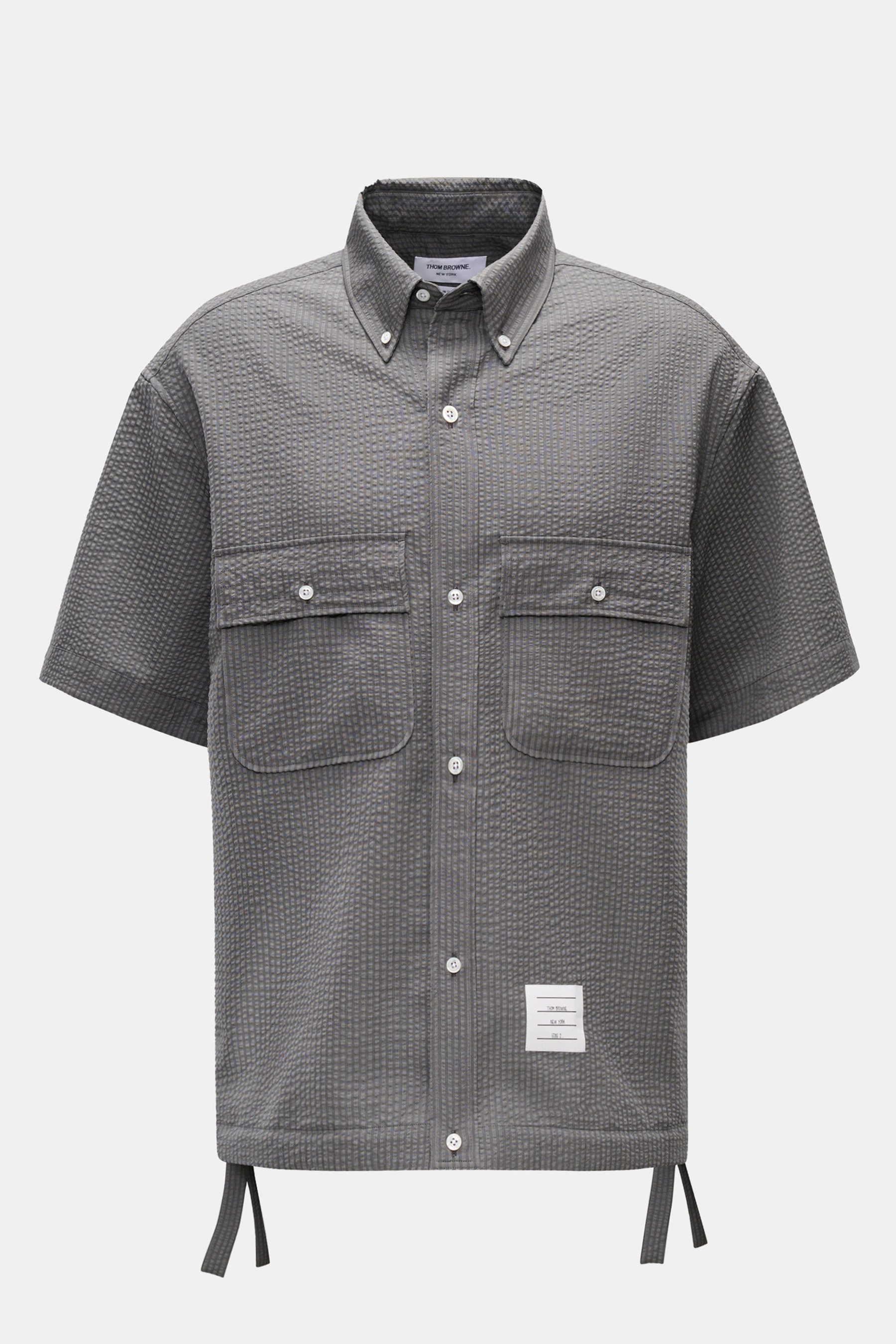 Front view of Thom Browne Seersucker short sleeve shirt button-down collar dark grey in textured pure wool seersucker with oversized fit, buttoned breast pockets, adjustable hem, and signature label.

Description: <p>Maximum comfort meets a distinctive si