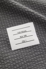Thom Browne Seersucker-Kurzarmhemd Button-Down-Kragen dunkelgrau Detailaufnahme der strukturierten Wolle mit weißem Markenlabel, Nahaufnahme.