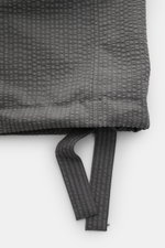 Detailaufnahme des Saum mit regulierbarem Band des Thom Browne Seersucker-Kurzarmhemds Button-Down-Kragen dunkelgrau aus strukturiertem Woll-Seersucker.