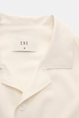 Ché Short sleeve shirt 'Valbonne' Cuban collar cream shown from above, featuring oversized fit, Cuban collar, French button placket, soft viscose fabric, and contrasting sleeve details. The short sleeve shirt 'Valbonne' by CHÉ encapsulates summery nonchal