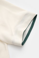 Close-up side view of the sleeve of the Ché Short sleeve shirt 'Valbonne' Cuban collar cream, showing the contrasting inner cuff stripes. The short sleeve shirt 'Valbonne' by CHÉ encapsulates summery nonchalance: Oversized fit, with a Cuban collar and dis