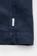 Nahaufnahme des Saumabschnitts mit kleinem Weblabel der 04651/ A trip in a bag Leinen-Kurzarmhemd Kubanischer Kragen navy aus reinem Leinen.