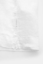 Close-up of the straight hem with short vents and small woven label of the 04651/ A trip in a bag Linen short sleeve shirt Cuban collar white, shot from the bottom side.

Description: <p><span class="_fadeIn_m1hgl_8">Effortless </span><span class="_fade