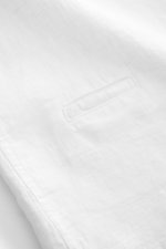 White linen fabric close-up showing texture and a small coin pocket, photographed from a top-down angle. 04651/ A trip in a bag Linen short sleeve shirt Cuban collar white. <p><span class="_fadeIn_m1hgl_8">Effortless </span><span class="_fadeIn_m1hgl_8">l