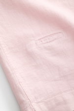 Nahaufnahme eines roséfarbenen 04651/ A trip in a bag Leinen-Kurzarmhemd Kubanischer Kragen, detailreich fotografiert von der Seitennaht mit Münztasche, feiner Leinenstruktur und kurzem Saumschlitz, luftig und leicht für sommerliche Looks.