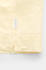 Alt-Tag (124 Zeichen): Nahaufnahme des Saums mit kleinem Weblabel des 04651/ A trip in a bag Leinen-Kurzarmhemd Kubanischer Kragen pastellgelb.