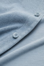 Nahaufnahme des 04651/ A trip in a bag Frottee-Kurzarmhemd 'Terry Cuba' rauchblau, Detail von Knöpfen und Baumwoll-Frottee-Struktur.