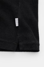 Schwarzes Detailfoto des Saum mit kleinem Weblabel des 04651/ A trip in a bag Frottee-Kurzarmhemd 'Terry Cuba' aus Baumwoll-Frottee.
