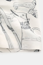 Nahaufnahme des markanten Allover-Prints des Jacquemus Kurzarmhemds 'Cocktail' offwhite/grau/schwarz gemustert, Mix aus Viskose und Leinen, Regular Fit, offener Kragen, dekorative J-Schlaufe, fotografiert aus seitlicher Perspektive.