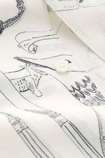 Nahaufnahme des Jacquemus Kurzarmhemds 'Cocktail' offwhite/grau/schwarz gemustert, fotografiert von oben, Mix aus Viskose und Leinen, Regular Fit, offener Kragen, markanter Allover-Print, dekorative J-Schlaufe.