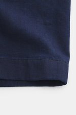 Jacquemus Denim Kurzarmhemd dunkelblau aus reiner Baumwolle, Regular Fit, offener Kragen, Brusttasche, J-Schlaufe, Nahaufnahme Stoffstruktur.