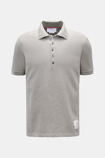 Vorderansicht des Thom Browne Poloshirts grau meliert aus reiner Baumwolle, Slim Fit mit klassischem Polokragen, Fünf-Knopf-Leiste, Rippbündchen am Ärmel und markentypischem Streifen-Logo.
