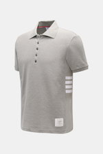Thom Browne Poloshirt grau meliert, Slim Fit, reine Baumwolle, klassischer Polokragen, Fünf-Knopf-Leiste, seitlich Streifen-Logo, seitliche Ripp-Einsätze, schräg von vorne.