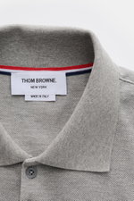 Nahaufnahme aus schräger Draufsicht auf den klassischen Polokragen des Thom Browne Poloshirt grau meliert aus reiner Baumwolle mit Fünf-Knopf-Leiste.