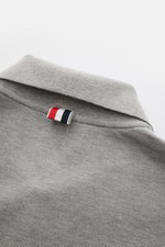 Thom Browne Poloshirt grau meliert, Nahaufnahme Rückseite mit klassischem Polokragen und markentypischem Streifen-Logo aus reiner Baumwolle.
