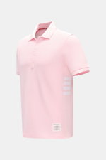 Thom Browne Poloshirt rosé, Slim Fit, aus reiner Baumwolle mit klassischem Polokragen, Fünf-Knopf-Leiste, Rippbündchen, Streifen-Logo, seitliche elastische Einsätze, seitliche Perspektive.