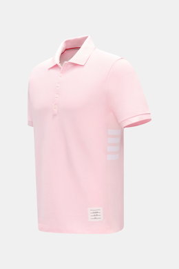 Thom Browne Poloshirt rosé, Slim Fit, aus reiner Baumwolle mit klassischem Polokragen, Fünf-Knopf-Leiste, Rippbündchen, Streifen-Logo, seitliche elastische Einsätze, seitliche Perspektive.