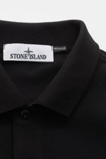 Close-up front top view of Stone Island Poloshirt schwarz, a classic black polo made from pure cotton piqué with a structured feel, garment dyed, slim fit, typical polo collar, smooth button placket, Stone Island web label, flexible sleeve cuffs, and side