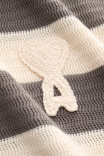 Nahaufnahme des Ami Paris Kurzarm-Strickpolo grau/creme gestreift mit Streifenmuster, griffiger Baumwolle und Herz-Stitching.