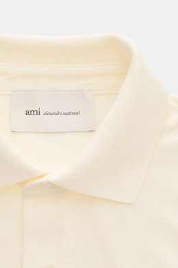 Close-up front view of Ami Paris Polo shirt cream showing signature collar, three-button placket, and textured piqué cotton fabric with logo stitching. 

Description: <p>A casual classic among polo shirts: This piqué model in pure cotton with three-dimens