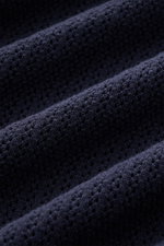 Nahaufnahme des luftigen Strickmusters des Ché Kurzarm-Strickpolo 'Quinn' navy/hellbraun aus reiner Baumwolle, seitliche Perspektive.
