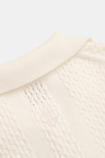 Nahaufnahme von Ché Kurzarm-Strickpolo 'Santino' creme mit grobem, asymmetrischem Strickmuster, gestricktem Polokragen und tonalem Logo, fotografiert von oben.