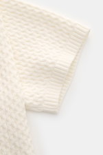 Nahaufnahme des rechten Ärmels vom Ché Kurzarm-Strickpolo 'Santino' creme, mit grobem, asymmetrischem Strickmuster aus reiner Baumwolle.