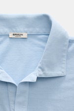 Nahaufnahme des hellblauen BRAUN Hamburg Jersey-Poloshirts aus reiner Baumwolle mit offenem Kragen, Slim Fit, seitlichen Saumschlitzen und feiner Jersey-Struktur, fotografiert von oben.