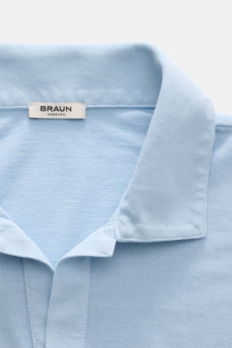 Nahaufnahme des hellblauen BRAUN Hamburg Jersey-Poloshirts aus reiner Baumwolle mit offenem Kragen, Slim Fit, seitlichen Saumschlitzen und feiner Jersey-Struktur, fotografiert von oben.