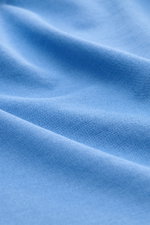 Das Bild zeigt eine Nahaufnahme der feinen Jersey-Baumwolle des BRAUN Hamburg Jersey-Poloshirt blau mit offener Kragenleiste, Slim Fit und seitlichen Saumschlitzen.