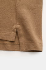 Nahaufnahme des seitlichen Saums mit Schlitz des braunen Polo Ralph Lauren Poloshirt aus reiner Baumwolle mit feiner Piqué-Struktur.