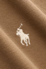 Polo Ralph Lauren Poloshirt braun, Nahaufnahme von der feinen Piqué-Struktur und dem weißen Poloreiter-Stitching auf Brusthöhe, reine Baumwolle.