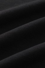 Close-up front perspective of black piqué cotton fabric showing texture and weave, from 04651/ A trip in a bag Poloshirt 'TP' schwarz. <p>Ob im Urlaub oder Office: 04651/ A TRIP IN A BAG bringt mit dem Poloshirt aus reiner Baumwolle lässiges Sommergefühl 