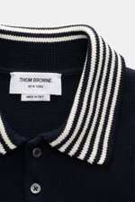 Nahaufnahme des Thom Browne Kurzarm-Strickpolo navy aus reiner Baumwolle, Regular Fit, mit gestricktem Polokragen und kontrastfarbenen Streifen, fotografiert von vorne.