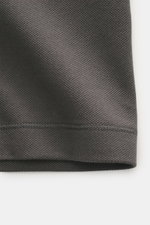 Close-up front view of dark grey Stone Island Polo shirt 'Stellina' showing piqué made of pure cotton with textured feel, garment dyed fabric, slim fit, typical polo collar, two-button placket with snap fasteners, and subtle Stellina stitching.