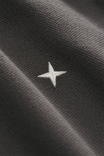 Close-up front view of Stone Island Polo shirt 'Stellina' dark grey showing piqué pure cotton fabric with textured feel, garment dyed, slim fit, typical polo collar, two-button placket with snap fasteners, and subtle Stellina stitching on the front.