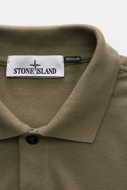 Stone Island Poloshirt oliv close-up from above, showing textured cotton piqué fabric, collar, button, and Stone Island label.