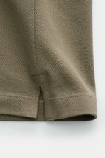 Stone Island Poloshirt oliv close-up of hem and side seam from front, made of pure cotton piqué with textured grip, slim fit, garment dyed.