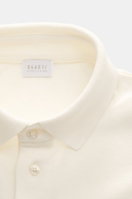 Nahe Aufnahme des cremefarbenen 04651/ A trip in a bag Poloshirt 'Wool TP' mit klassischem Polokragen, glatter Drei-Knopf-Leiste, Piqué aus Baumwolle und Wolle, weichem Griff, Slim Fit, kleinem Weblabel in der Seitennaht und komfortablen Rippbündchen.