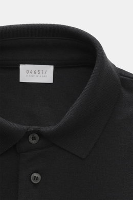 Nahaufnahme des schwarzen 04651/ A trip in a bag Poloshirts 'Wool TP' in Slim Fit, von oben fotografiert, Piqué aus Baumwolle und Wolle, weicher Griff, klassischer Polokragen, glatte Drei-Knopf-Leiste, kleines Weblabel in der Seitennaht, komfortable Rippb