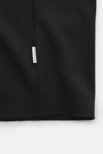 Nahaufnahme des schwarzen 04651/ A trip in a bag Poloshirt 'Wool TP' mit kleinem Weblabel, Piqué aus Baumwolle und Wolle, weichem Griff, Slim Fit, klassischem Polokragen, glatter Drei-Knopf-Leiste und komfortablen Rippbündchen.