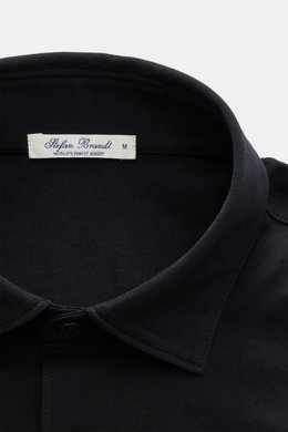 Nahaufnahme von Polokragen des Stefan Brandt Jersey-Poloshirt 'Luca' schwarz, Slim Fit, Jersey aus reiner Sea Island Baumwolle, weiche Haptik, Drei-Knopf-Leiste, kurze Saumschlitze, leicht verlängerte Rückseite.