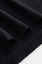 Nahaufnahme des schwarzen Stefan Brandt Jersey-Poloshirt 'Luca' Slim Fit mit Jersey aus reiner Sea Island Baumwolle, weicher Haptik, Polokragen, Drei-Knopf-Leiste, kurzen Saumschlitzen und leicht verlängerter Rückseite, Detailansicht der Stoffstruktur.